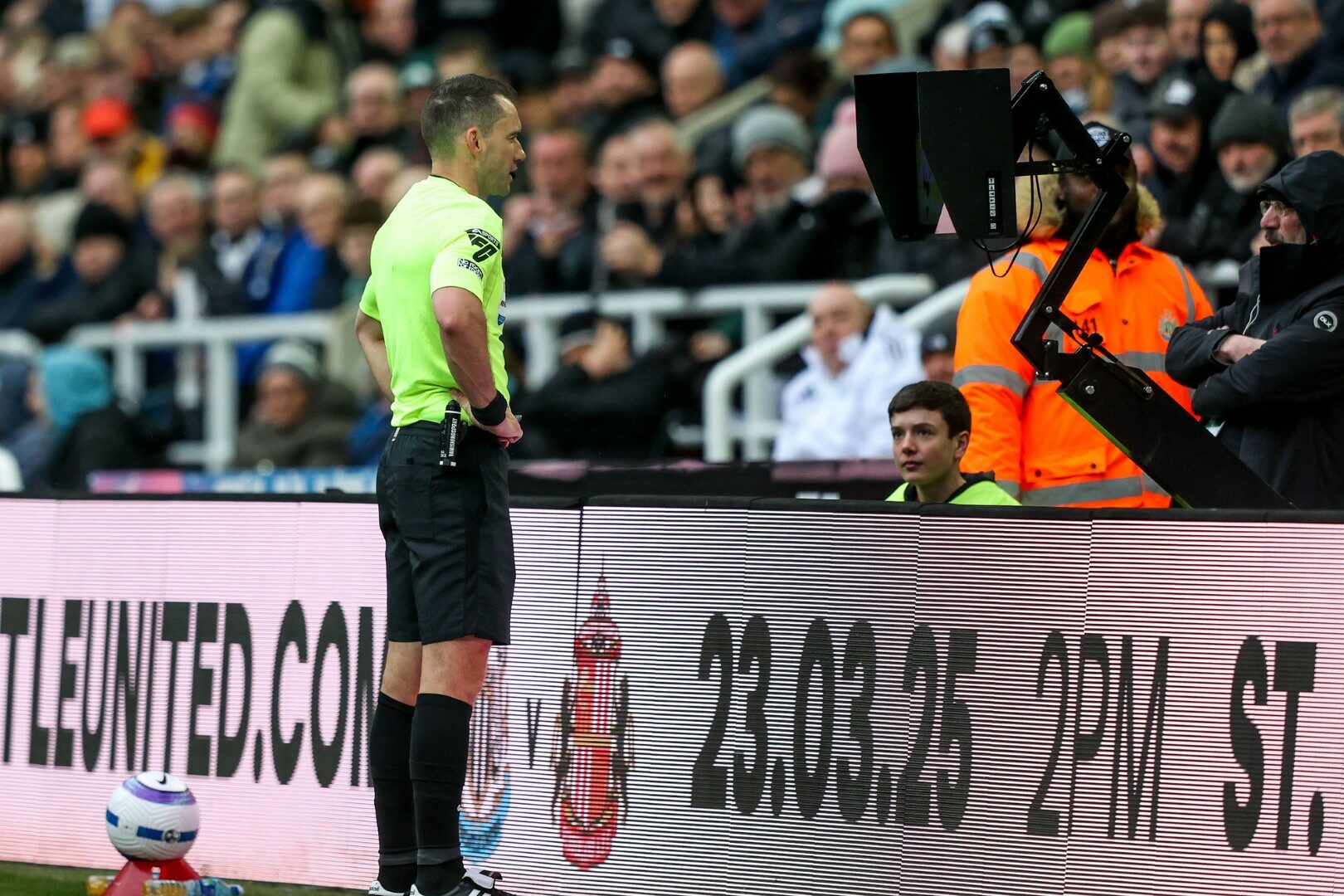 Een scheidsrechter die naar het VAR-scherm kijkt.